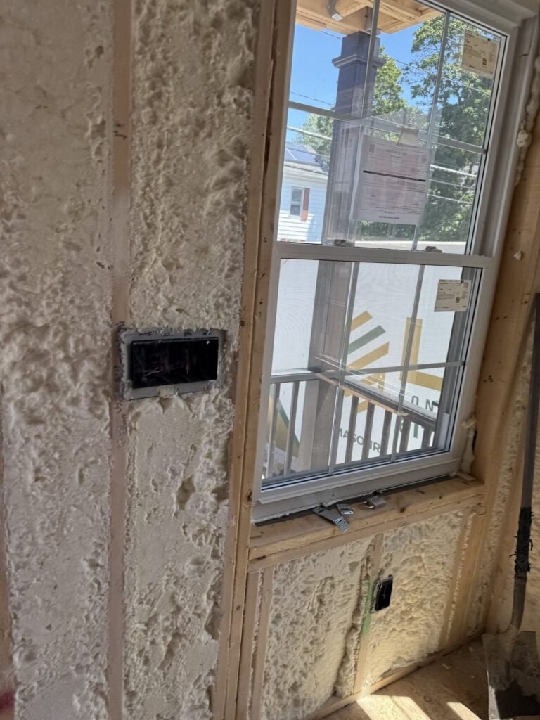 Spray foam around a window with a junction box on the side wall - HERS rating in Gardner, MA