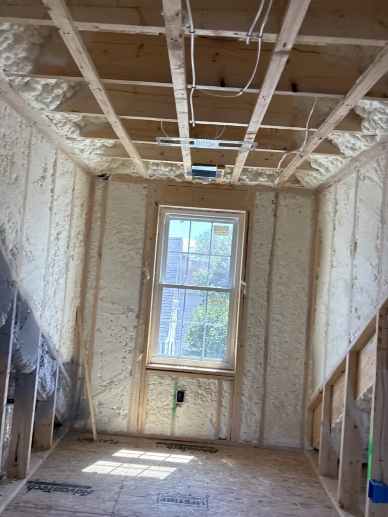 Narrow room with foamed walls and a strapped ceiling beside a stairway - spray foam insulation in Rowley, MA