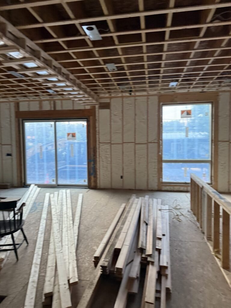Spray-foamed great room with sliding doors and lumber on the floor - HERS rating in Boxborough, MA