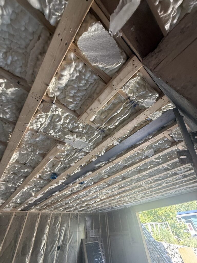 Spray foam sealing a sloped ceiling above wall framing in a basement-level room - spray foam insulation in Ayer, MA