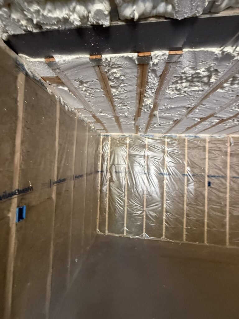 Spray foam sealing over a steel beam and ceiling joists in a stairwell - HERS rating in Arlington, MA