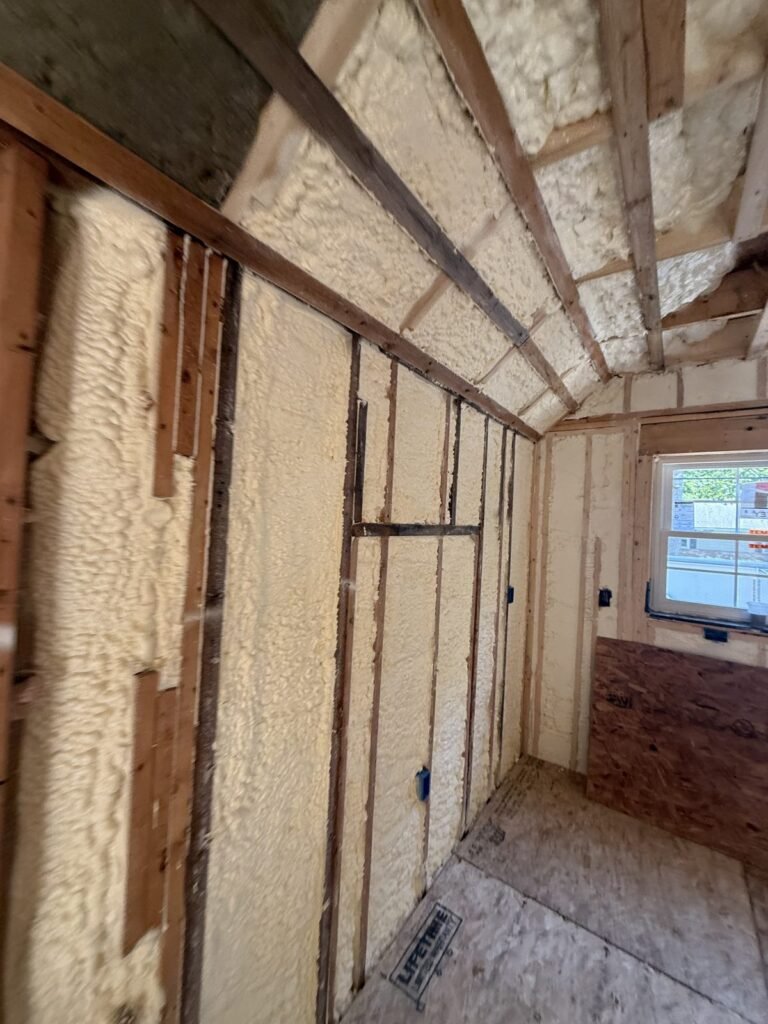 Sloped foamed rafters meeting a foamed wall in a narrow upstairs room - spray foam insulation in Eastham, MA