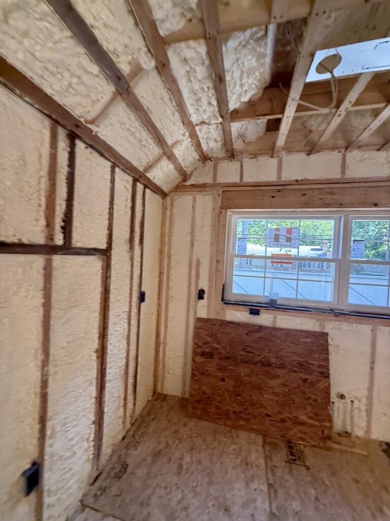 Foamed walls in a small room with plywood leaning by the window - HERS rating in Conway, MA