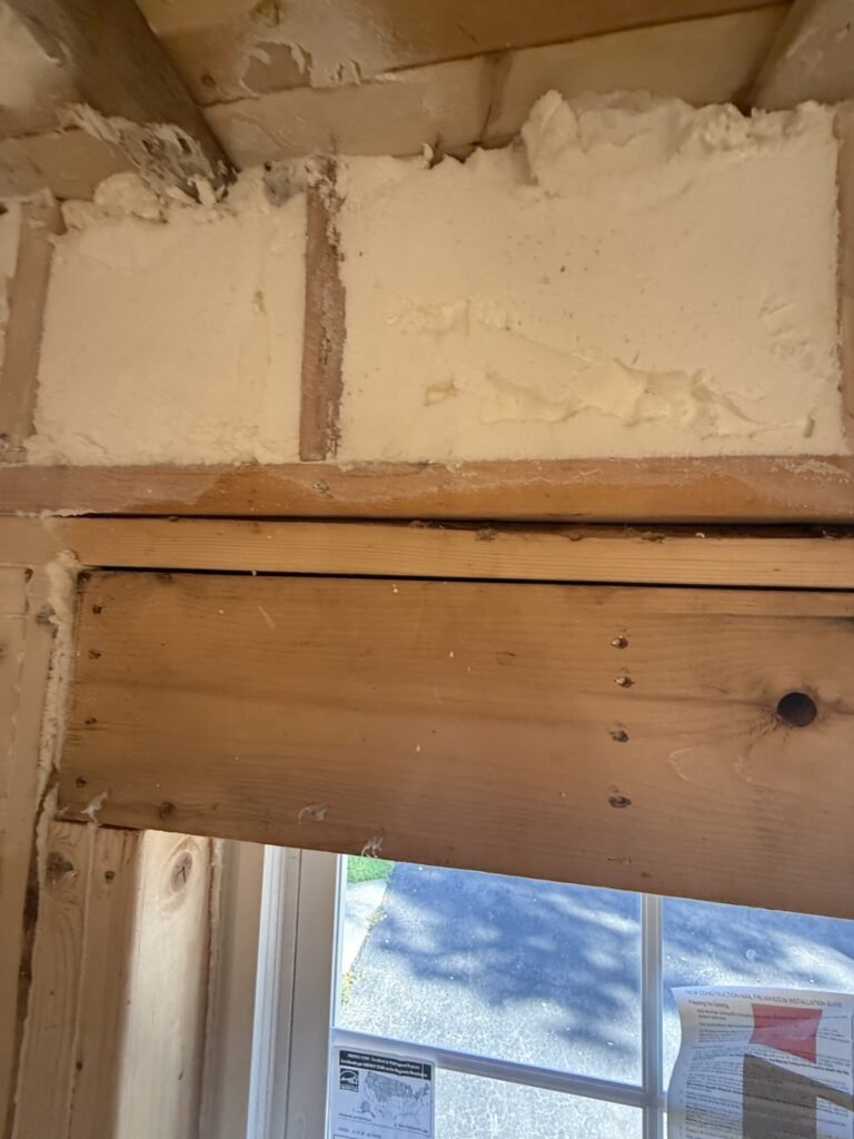 Spray foam sealing the rim joist above a window header - spray foam insulation in Lancaster, MA