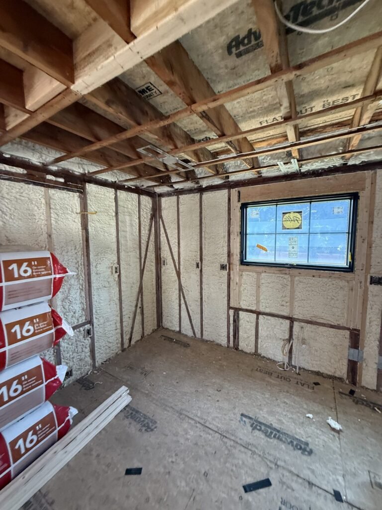 Foam-insulated room with a new window and insulation bags stacked inside - HERS rating in Burlington, MA