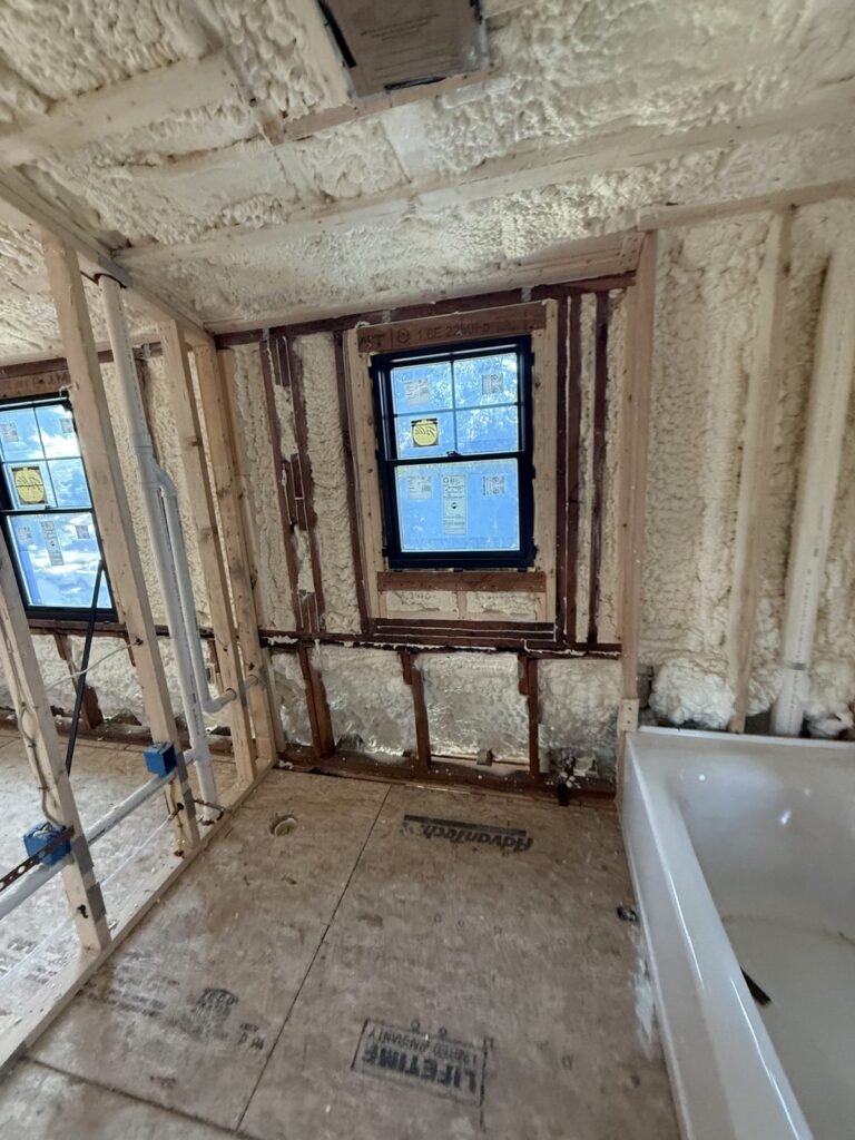 Foamed exterior wall with a black-framed window and plumbing rough-in - HERS rating in Abington, MA