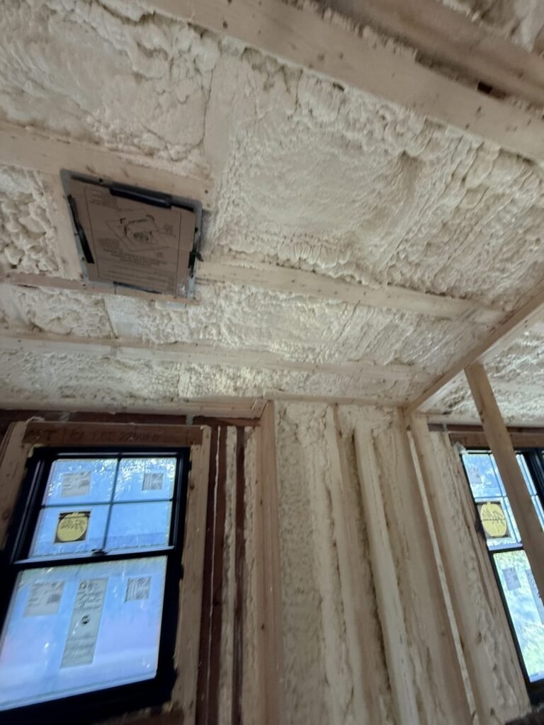 Sloped foamed ceiling with a vent box above a pair of windows - spray foam insulation in Monroe, MA