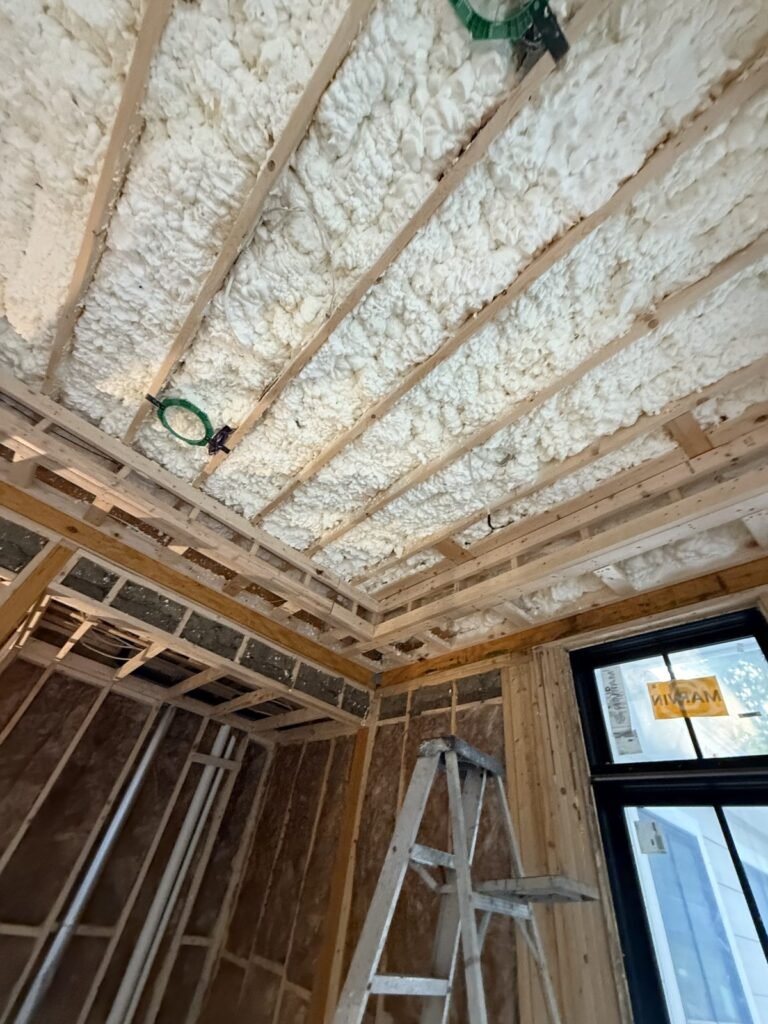 Foamed ceiling and walls around a black-framed window with a ladder nearby - HERS rating in Dracut, MA