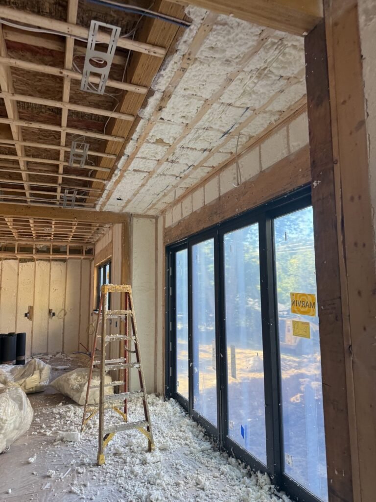 Spray foam on walls and ceiling around tall black-framed glass doors - HERS rating in Wellesley, MA