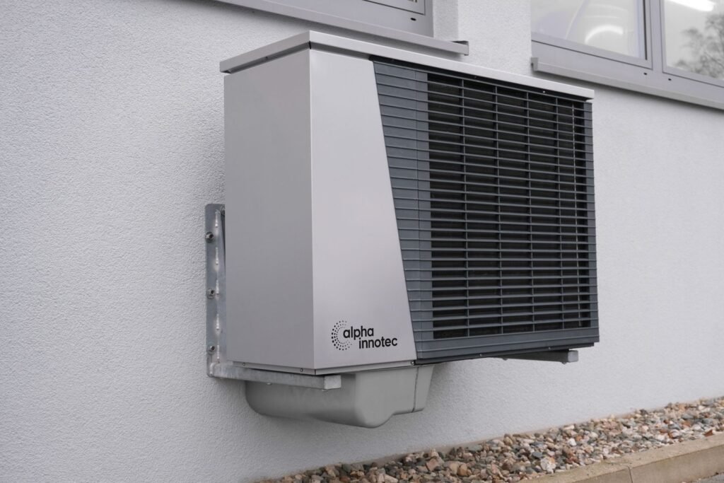 Close-up of a gray heat pump outdoor unit mounted on a wall - HERS rating in North Adams, MA